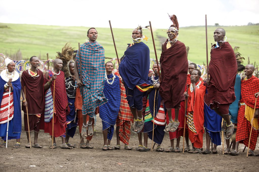 Maasai warrior in traditional attire performing a cultural dance in Tanzania