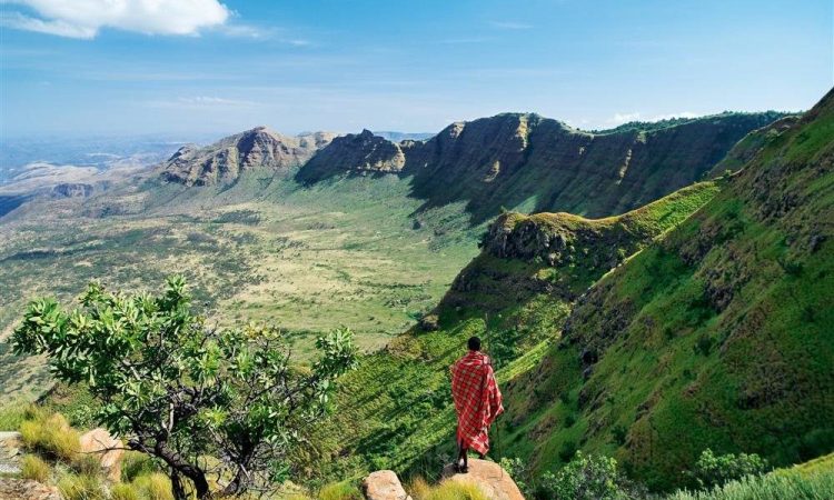 Maasai guide standing on a cliff overlooking the Great Rift Valley landscape during a Kenya adventure safari